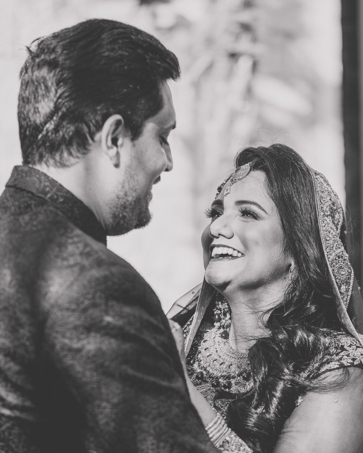 A couple shares an intimate winter moment outdoors in black and white photography.