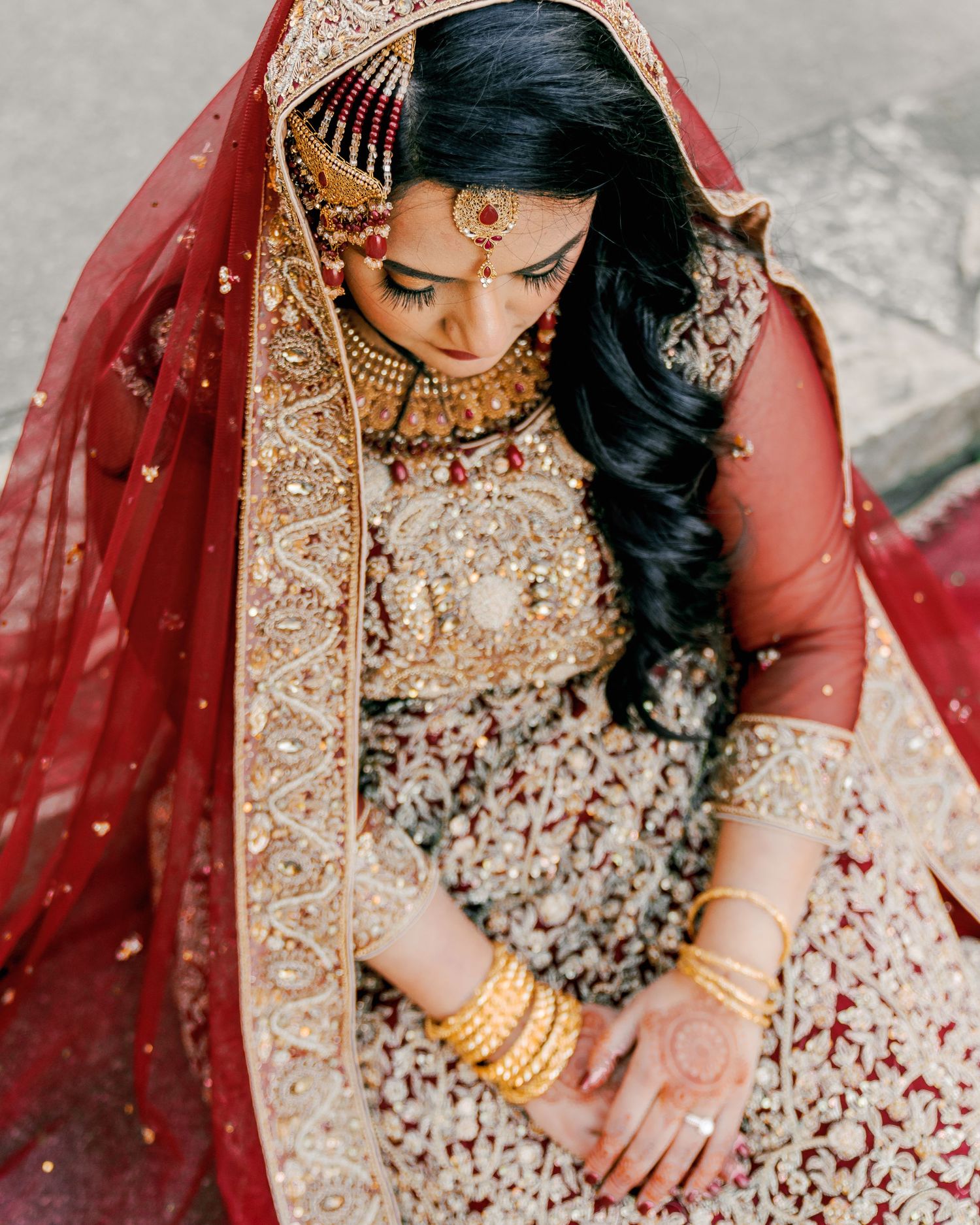 Close-up details of intricate bridal jewelry and embroidered red lehenga with gold embellishments.