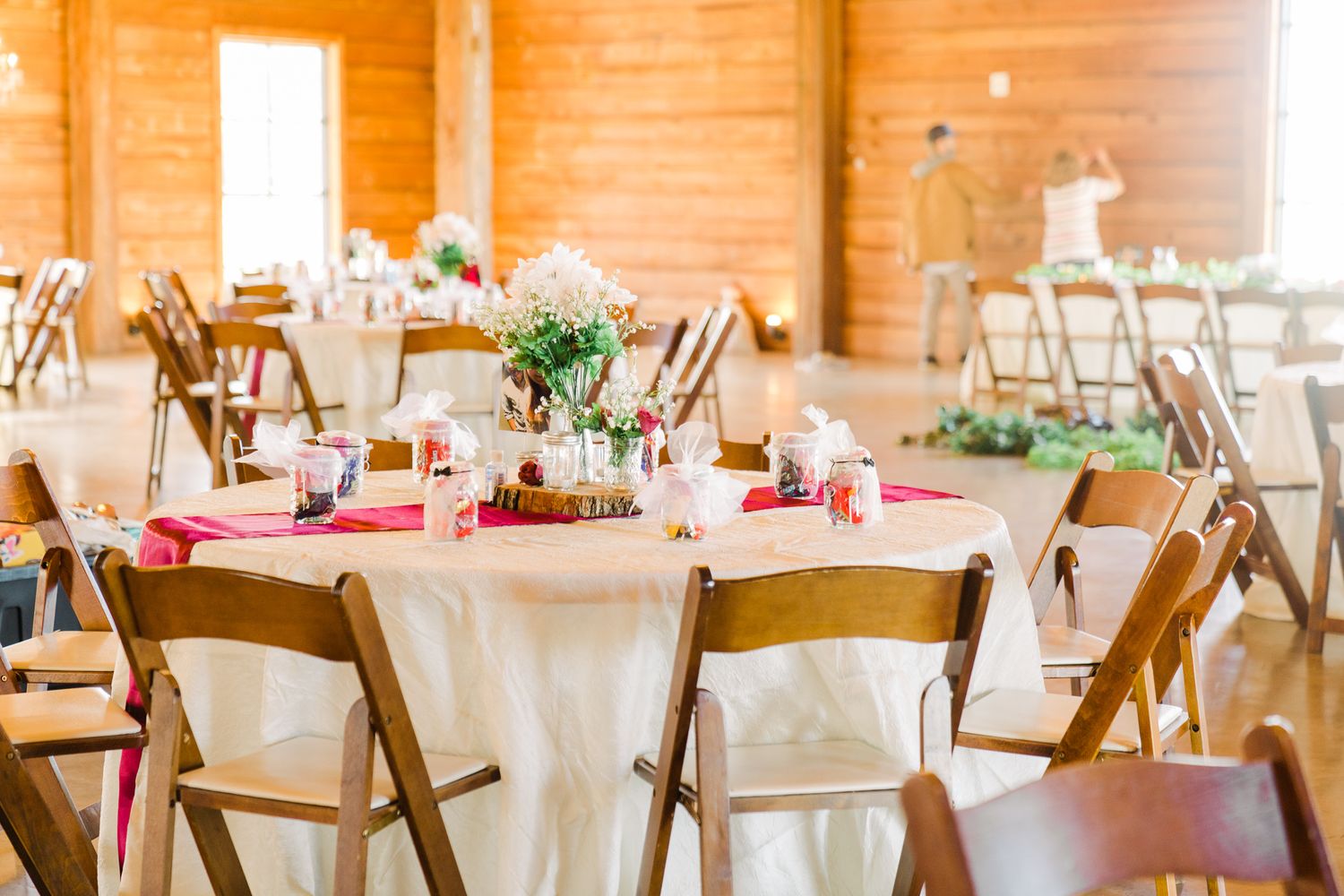 Rustic wedding reception venue with wooden beams and white chairs set up for an elegant celebration.