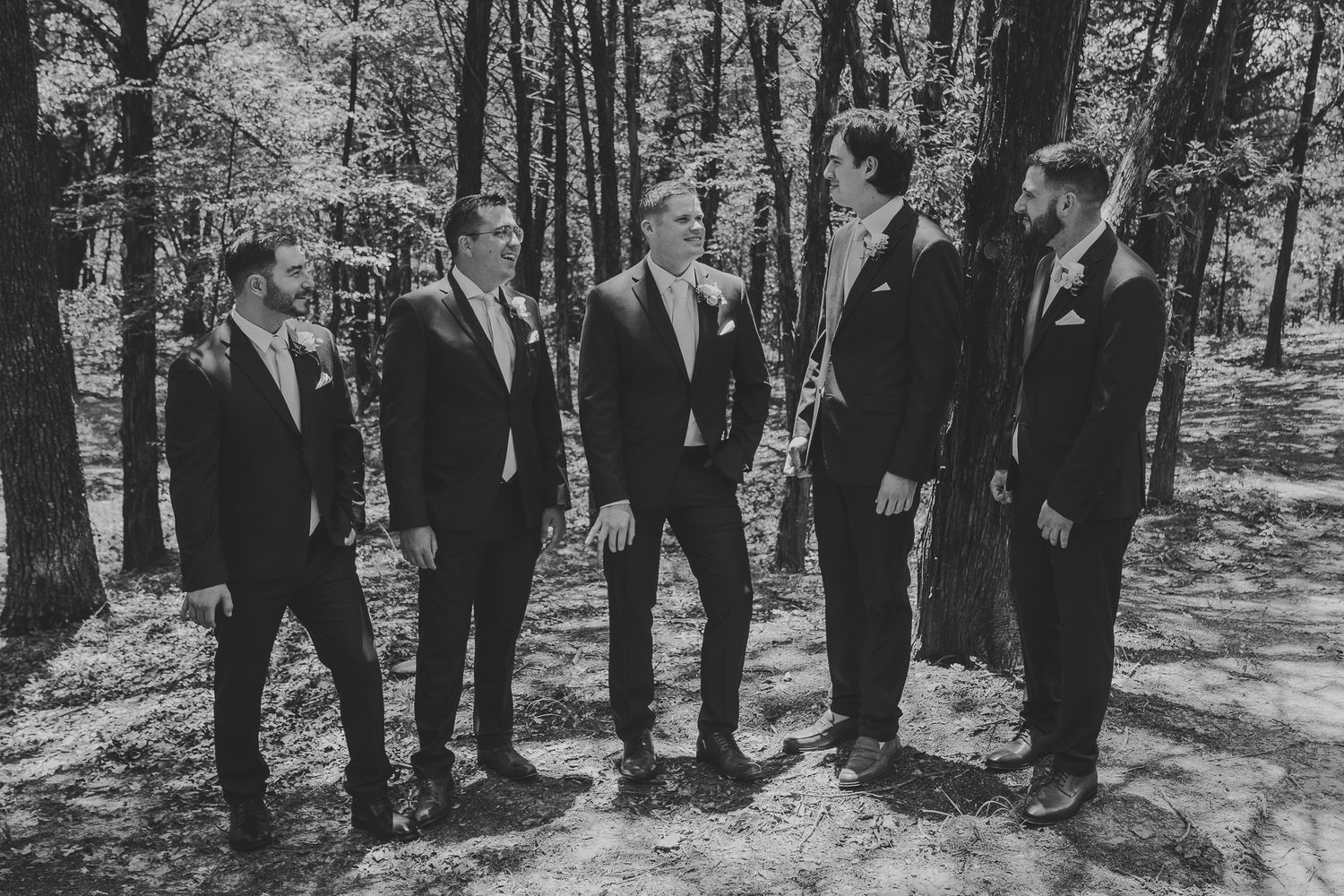 Black and white wedding party photo series showing group portraits in a wooded outdoor setting.