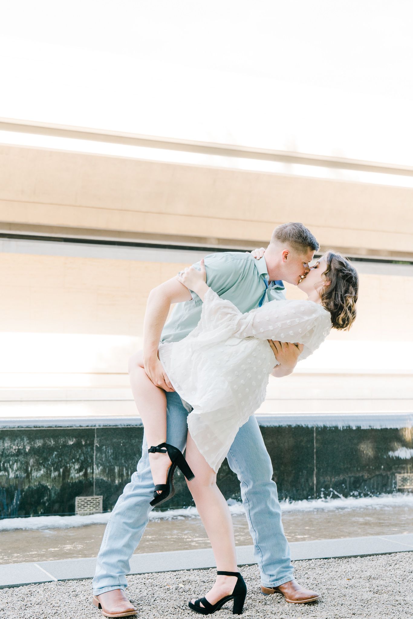 A couple in casual attire dancing in a romantic dip pose outdoors.