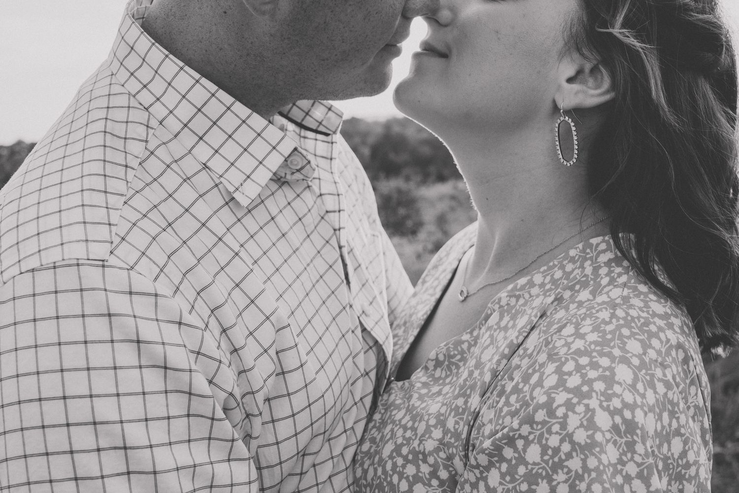 A tender romantic moment captured in black and white between a couple in a field.