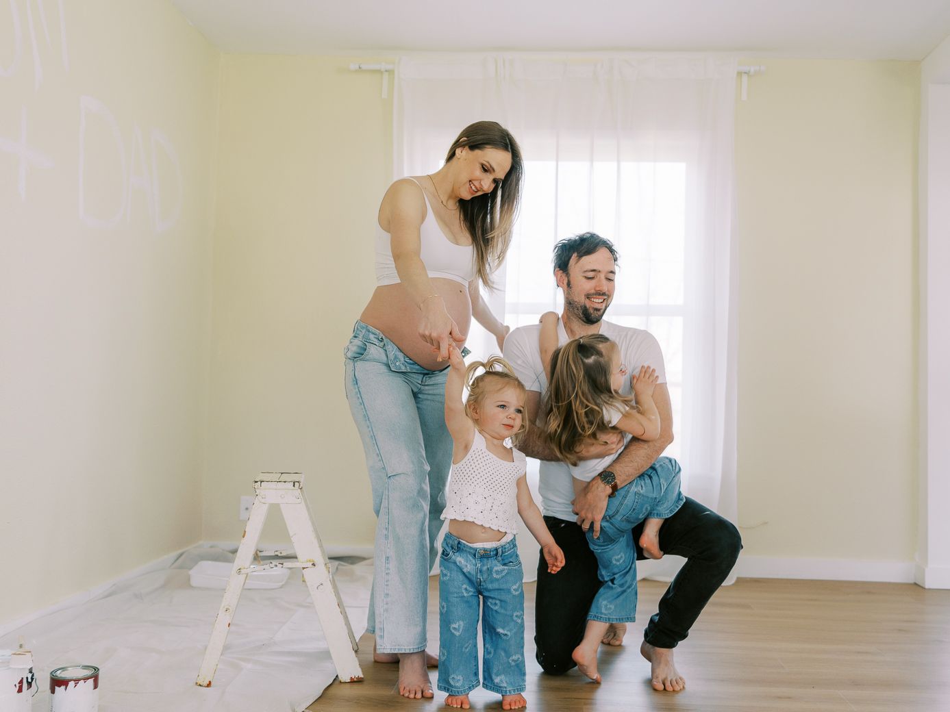 Family stands together in an empty room with a stepladder during home renovations.