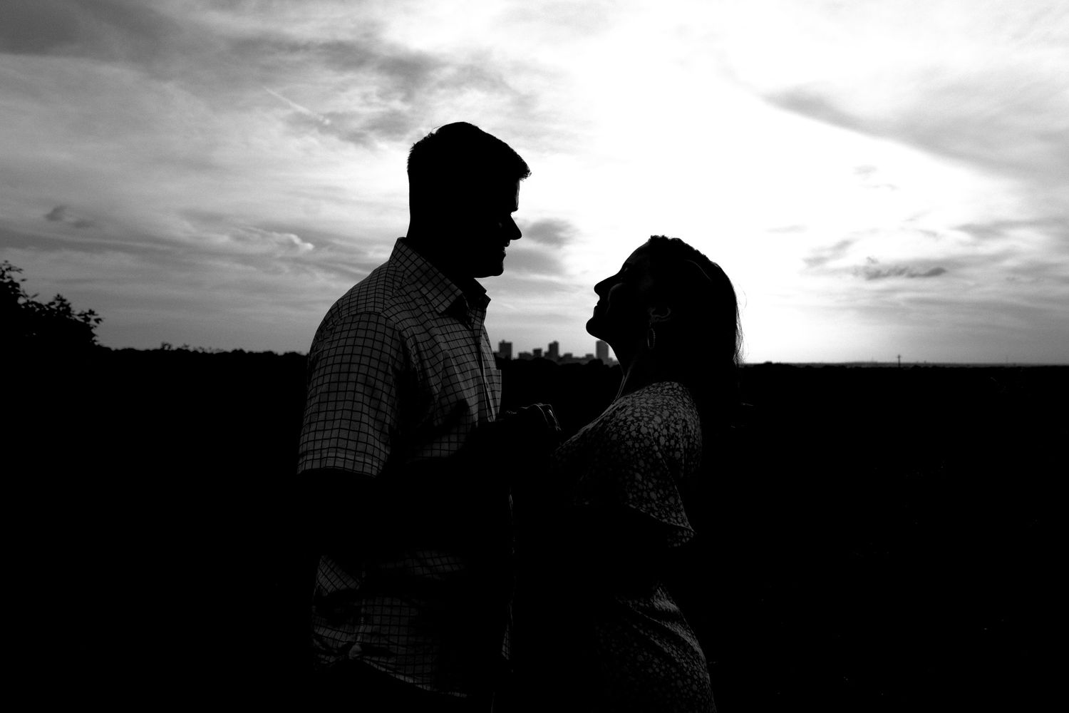 A series of black and white silhouettes of people against dramatic cloudy skies at sunset.