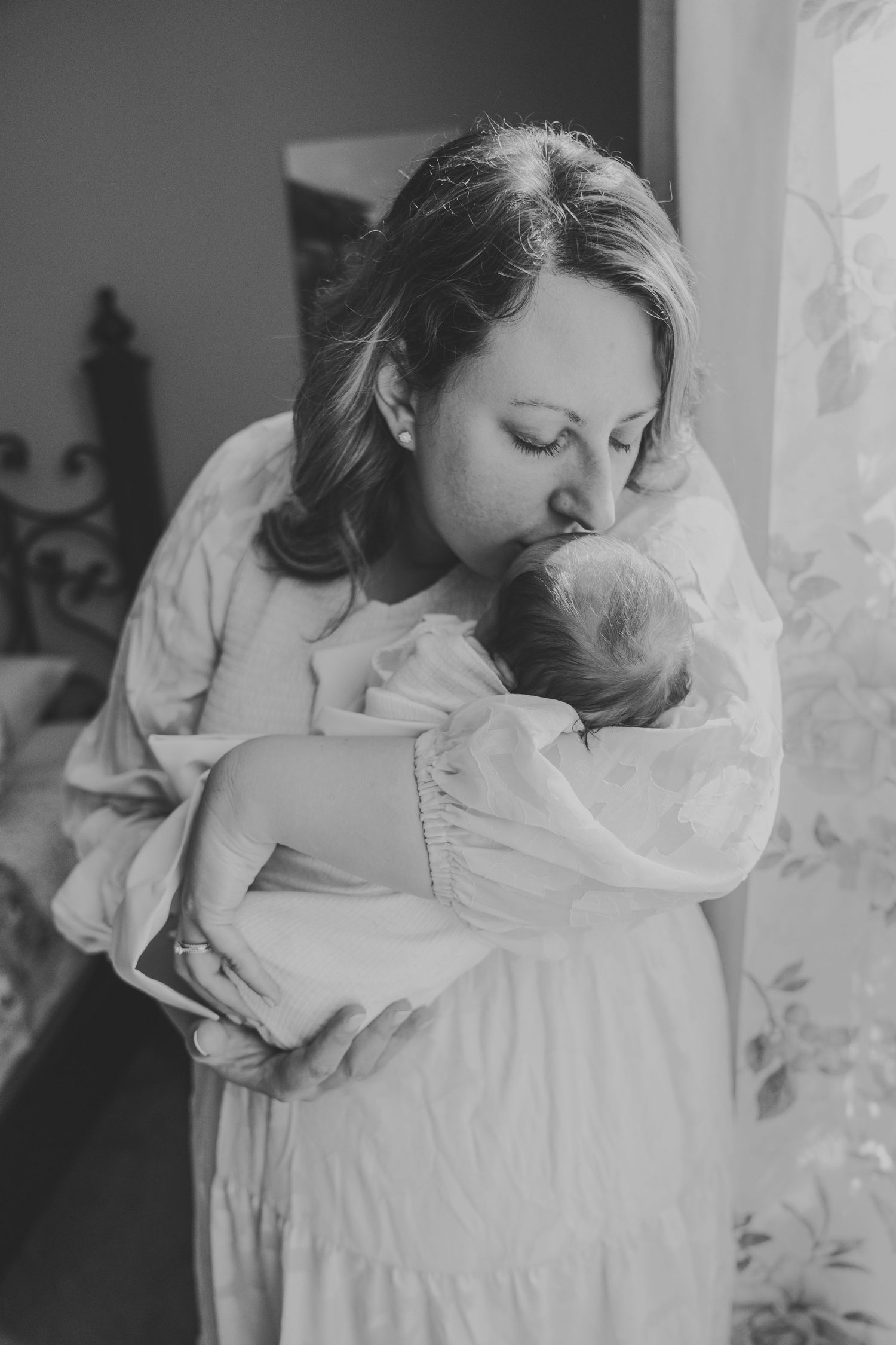 A tender black and white photo series showing a parent cradling and embracing a newborn baby in soft natural light.