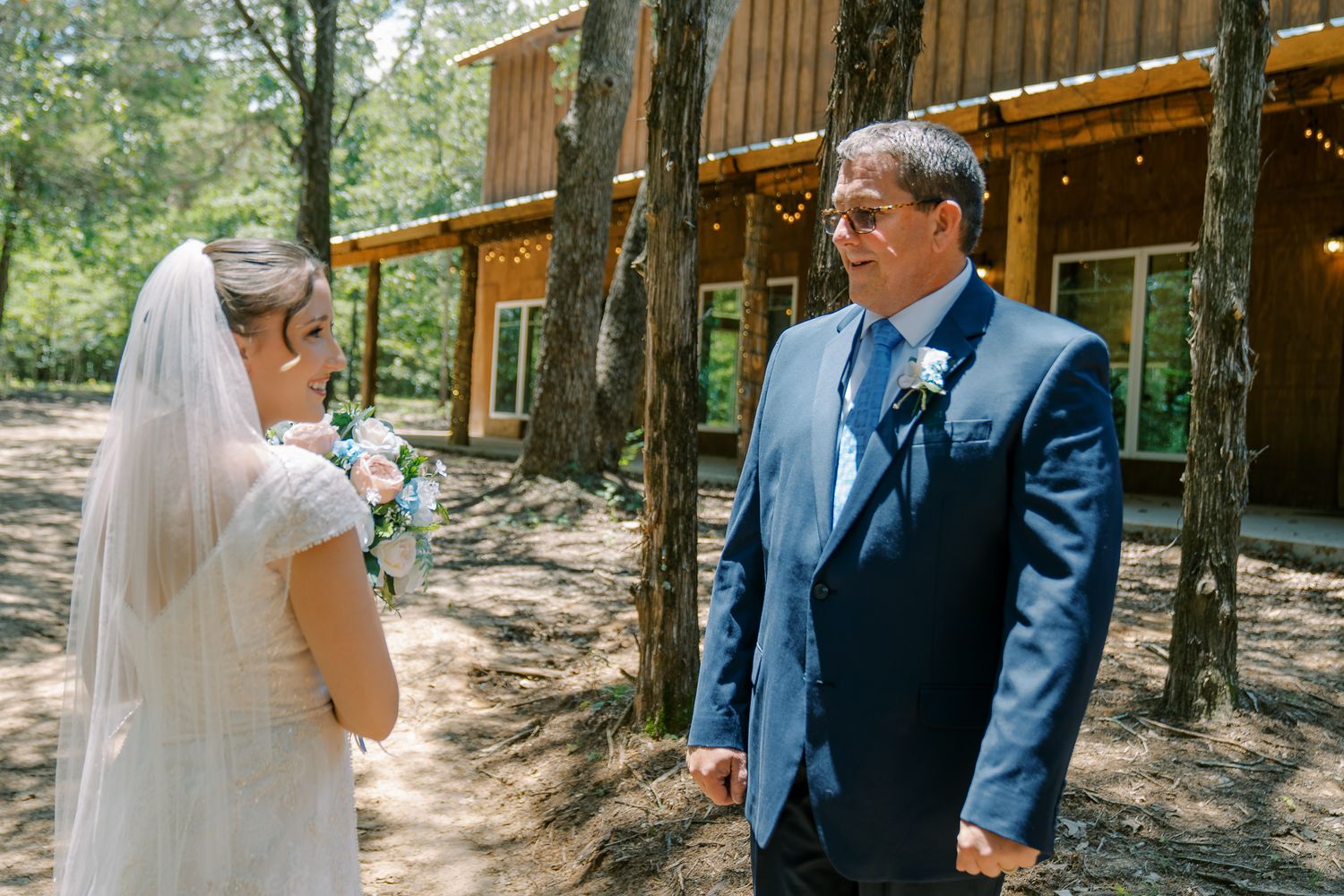 Two people share a special moment during a rustic outdoor wedding ceremony near a wooden cabin in the woods.