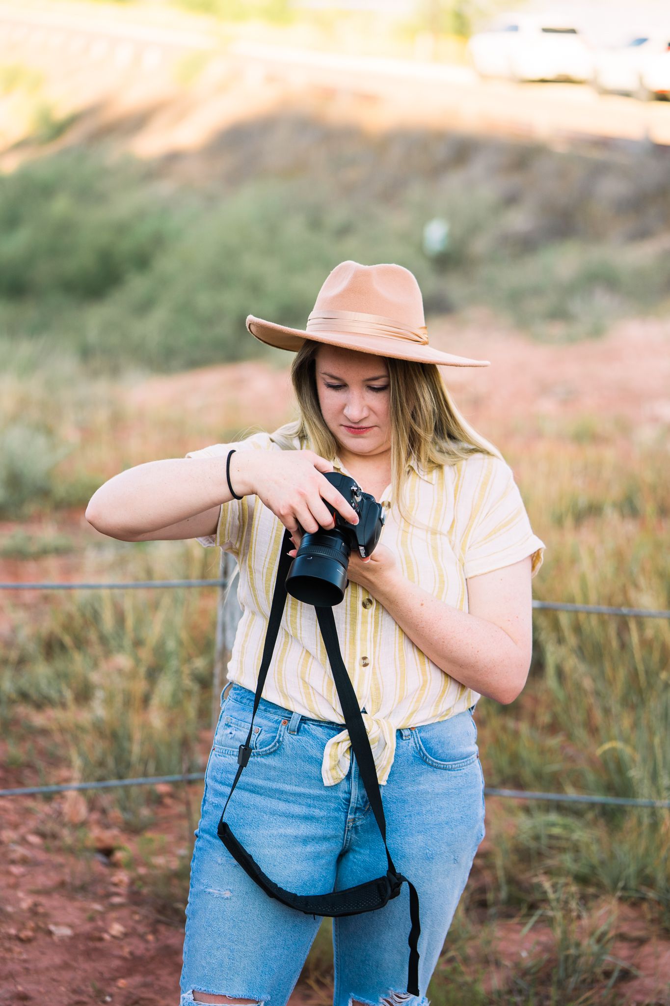 Person wearing peach hat and denim photographs in natural desert landscape during golden hour.