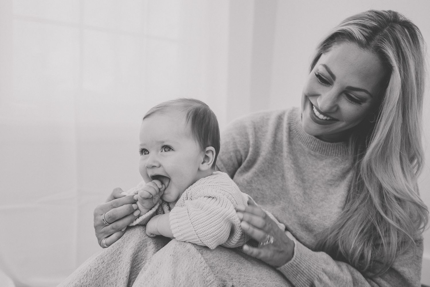 A series of black and white photos showing a baby laughing and playing with an adult in candid moments.
