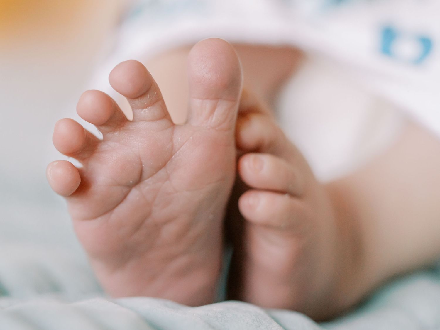 A close-up series of baby hands reaching and grasping in different positions against a soft white background.