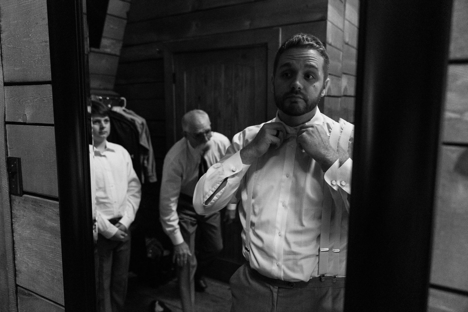 Black and white candid photos showing groomsmen getting ready for wedding celebration.