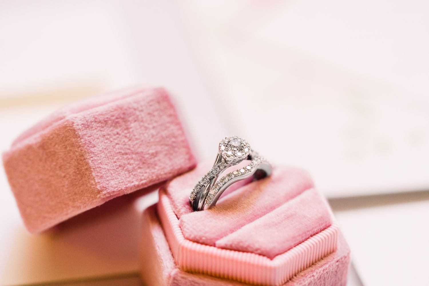 Pink marshmallows arranged on a white surface with a diamond engagement ring nestled among them.