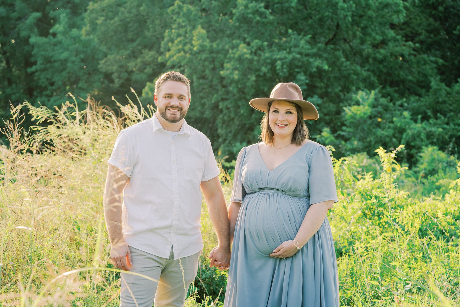 Couple walking together through a lush summer meadow with yellow wildflowers in bloom.