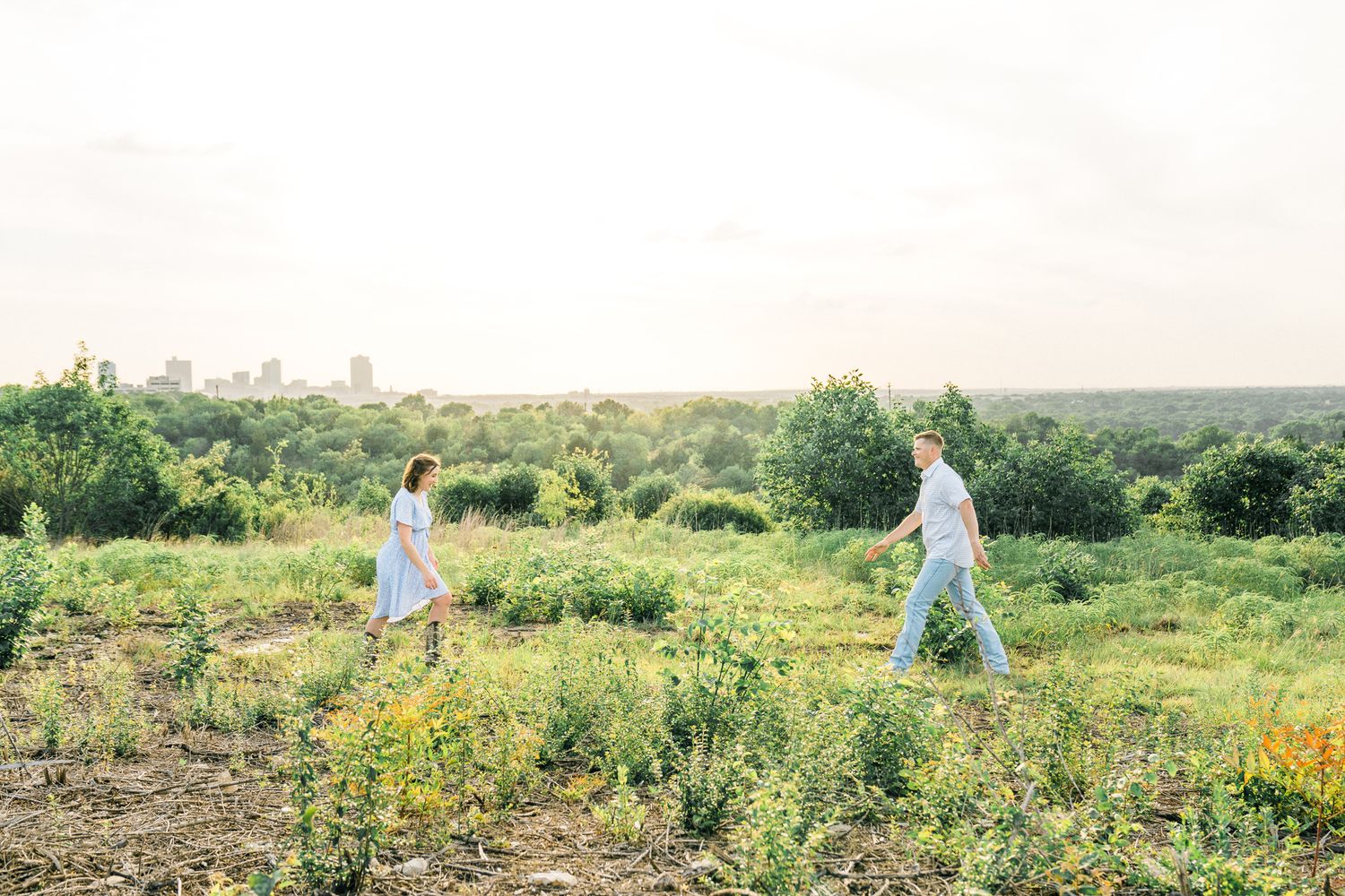 People walk through a scenic meadow filled with yellow wildflowers on a sunny day.