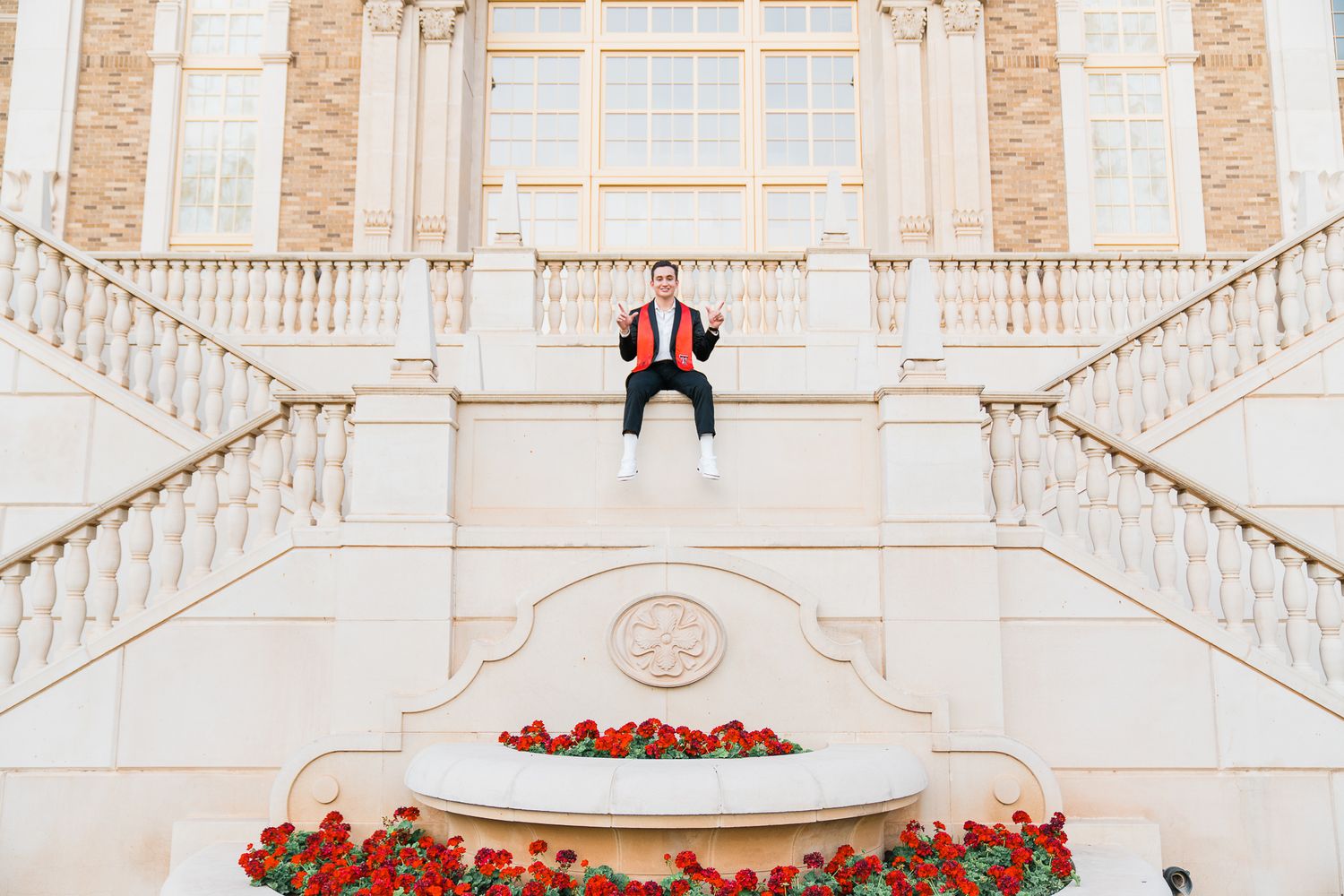 Grand white marble staircase with red floral decorations in an elegant ballroom setting.