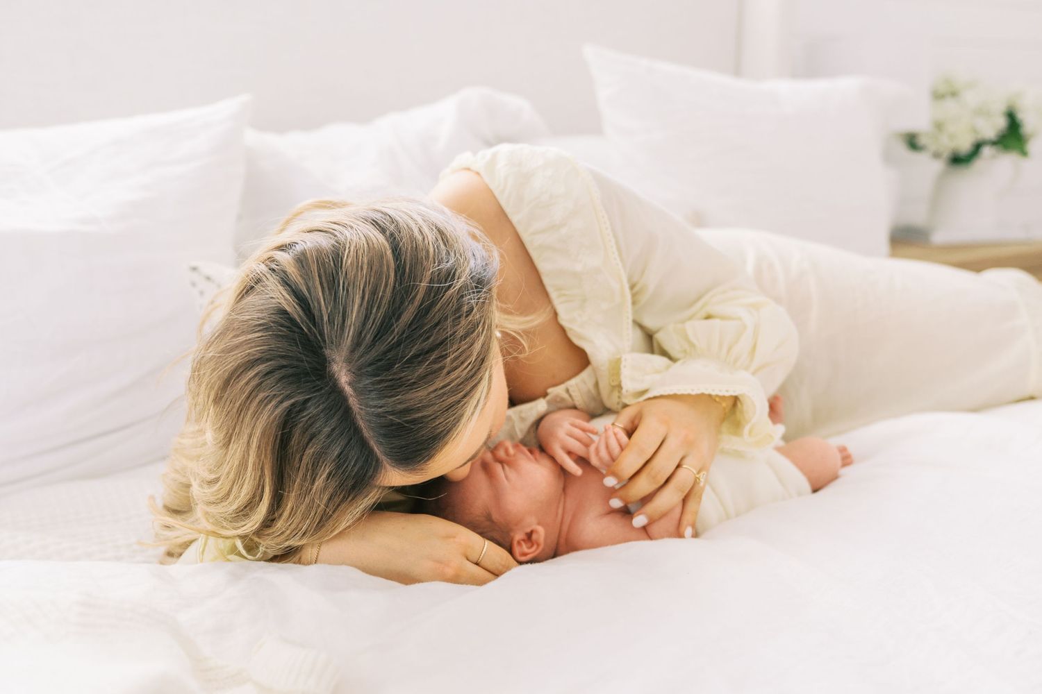 Tender family moments captured on a white bed in soft natural lighting.