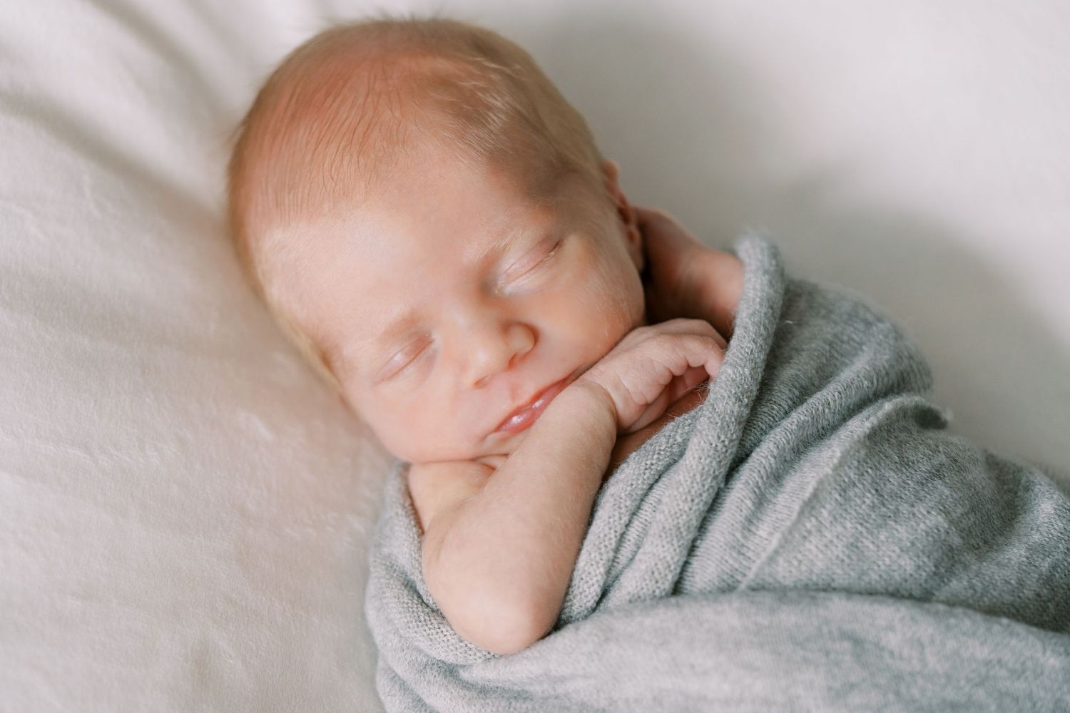 Sleeping newborn wrapped in a cozy gray blanket.