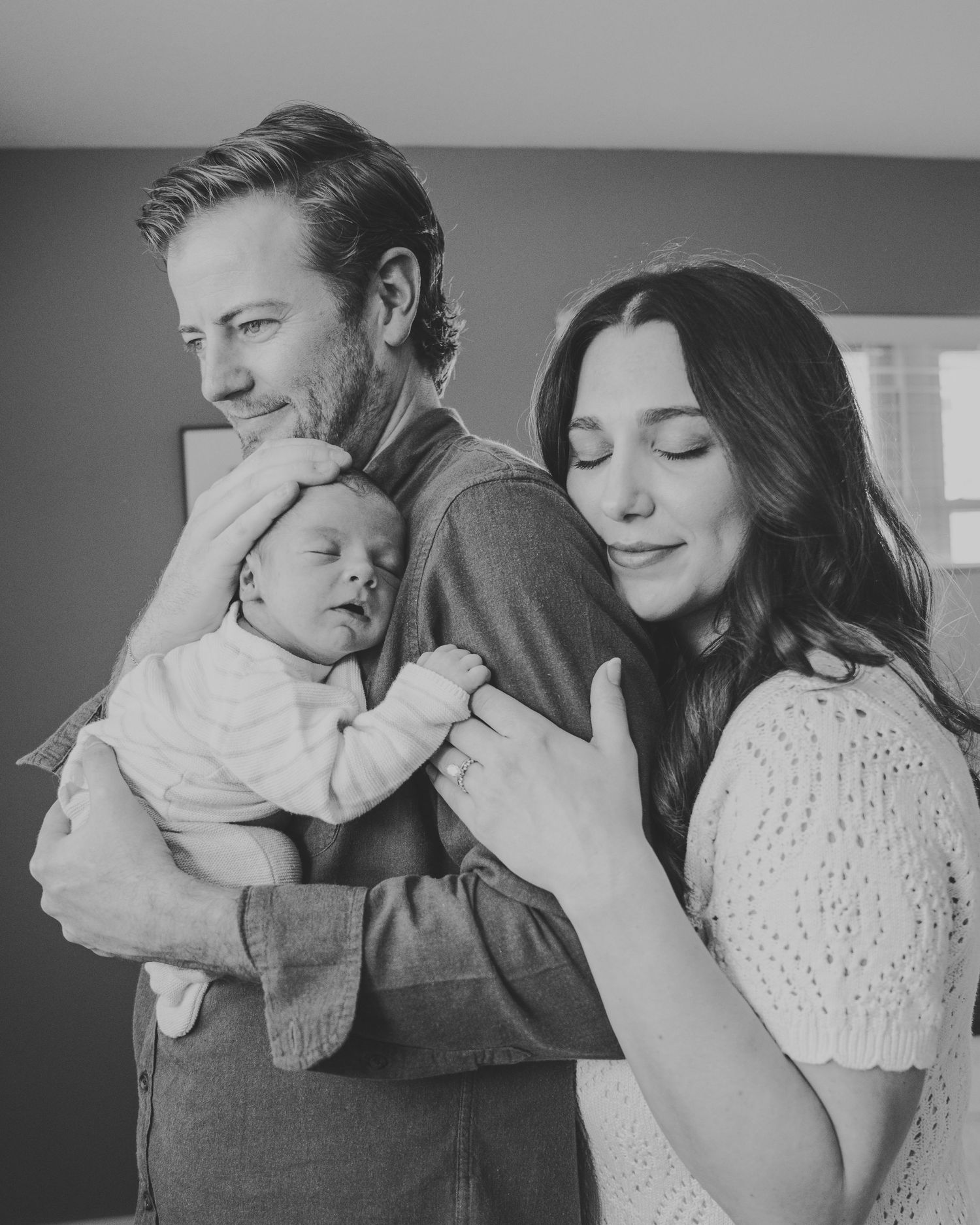 A series of intimate black and white family portraits showing tender moments between parents and their newborn baby.