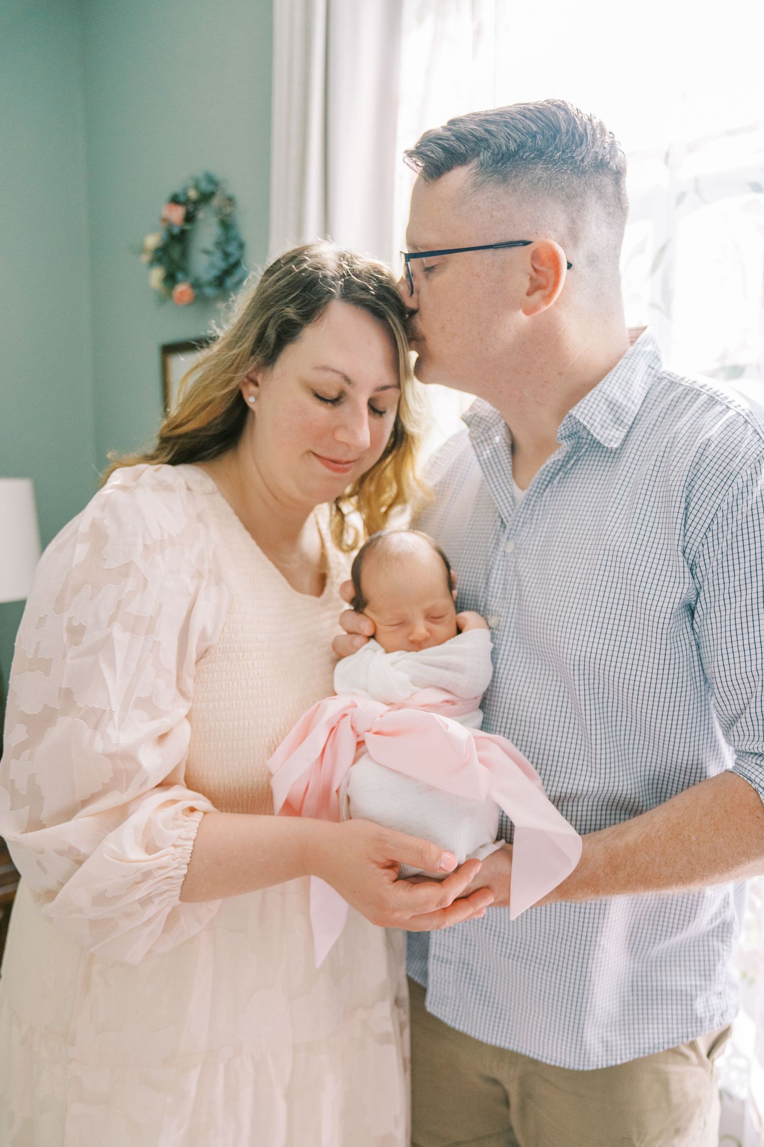 Sweet family moment captured in a series of intimate photos by a sunlit window.