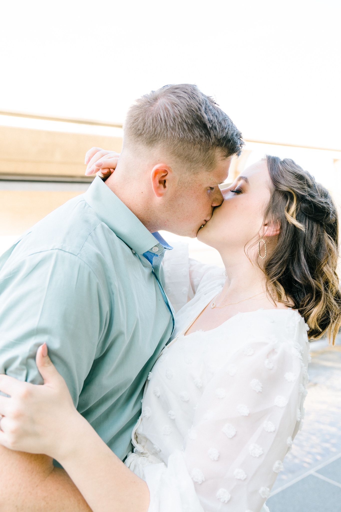 A romantic couple sharing a tender kiss in soft natural light.