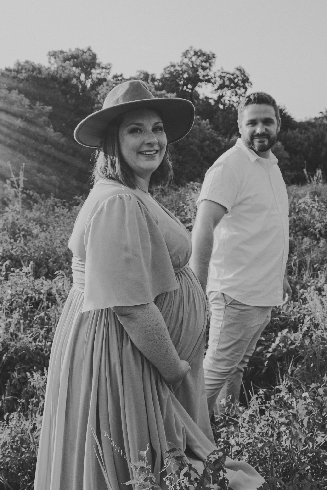 A couple poses together in a wildflower field wearing coordinated light blue and white outfits.