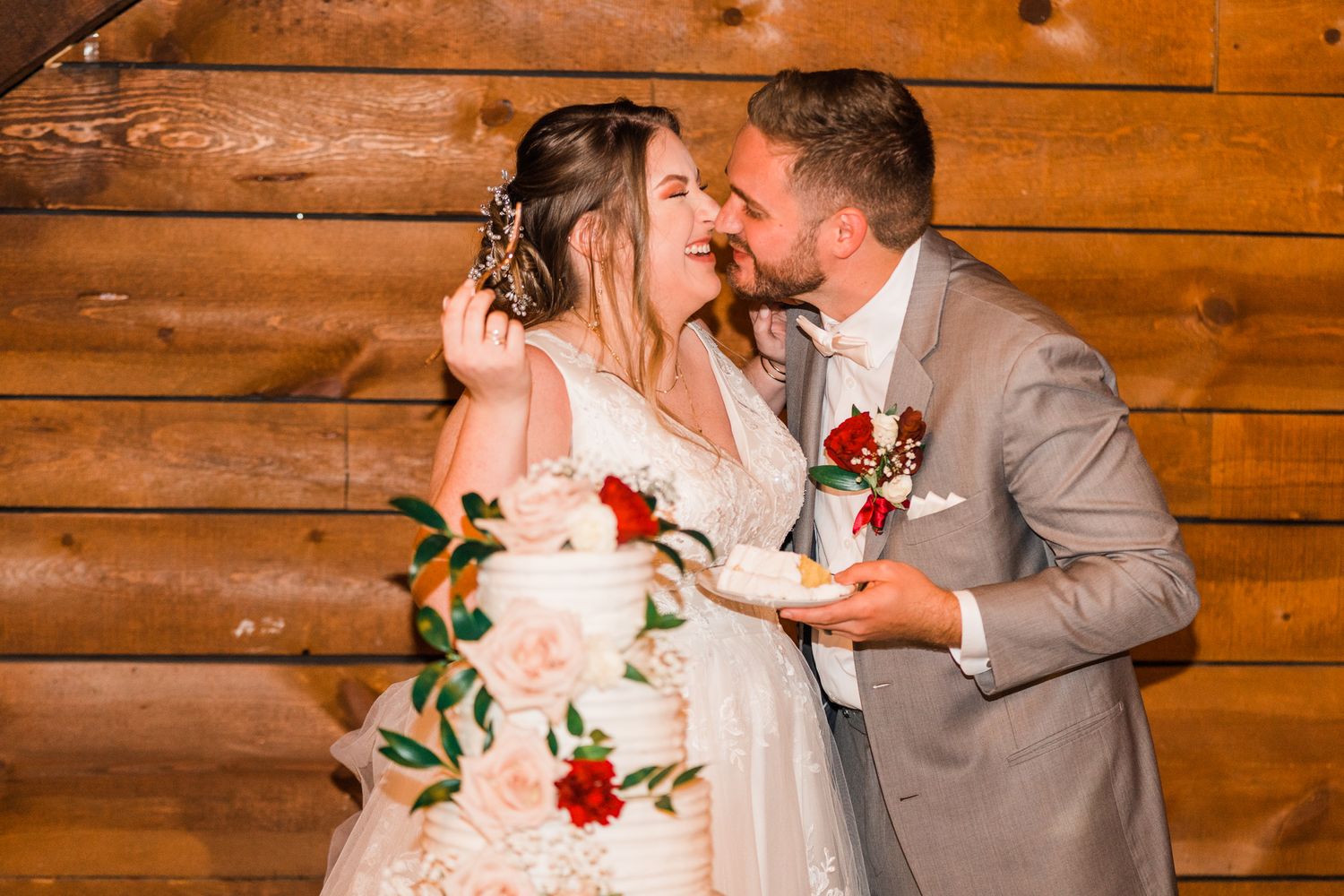 A romantic wedding moment unfolds in front of wooden paneled walls with chandelier lighting above.
