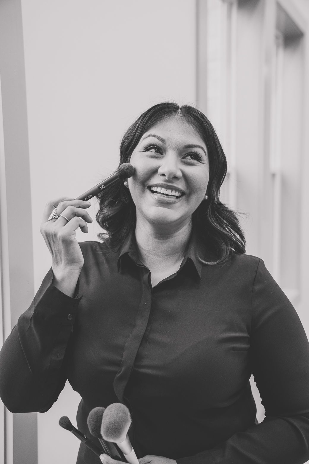 A series of four black and white photos showing someone in a black top making playful expressions and gestures.