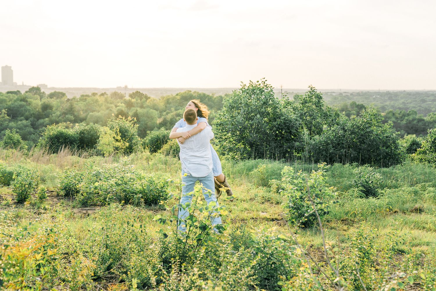 Wide landscape shot of figures dancing among wildflowers in a summer field.