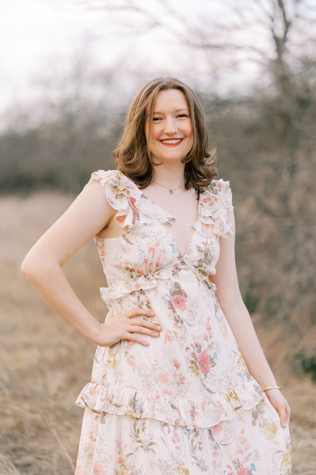 Floral ruffle dress being modeled in a dreamy outdoor field setting with soft natural lighting.