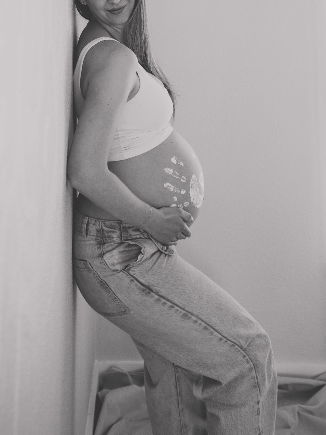 Black and white maternity portrait showing relaxed poses against a minimalist background.