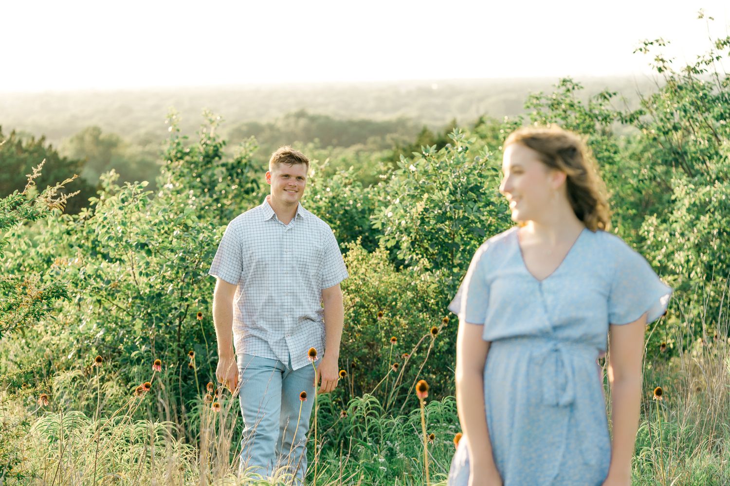 A couple shares tender moments together in a golden-lit meadow during sunset.