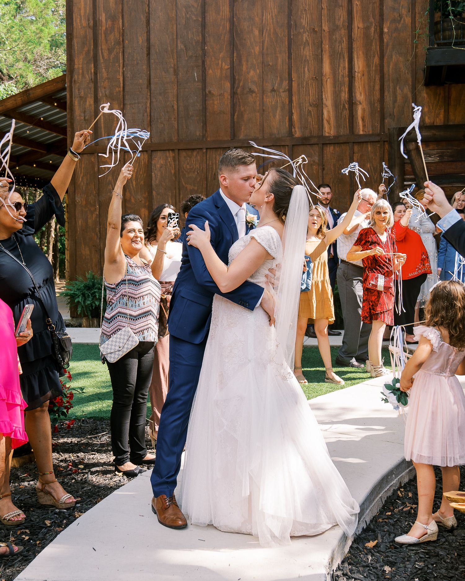 Wedding guests dance and celebrate in a rustic wooden barn venue during a reception party.