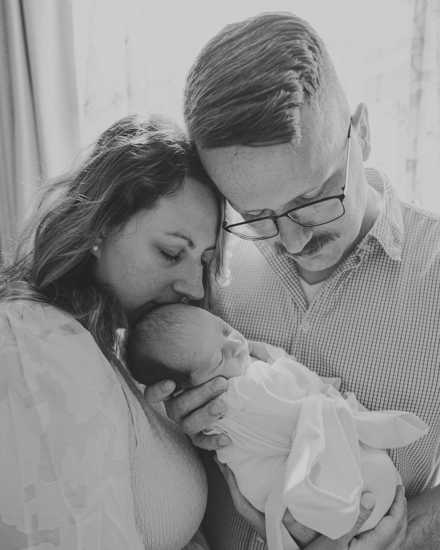 Black and white intimate family portrait session with soft window lighting.
