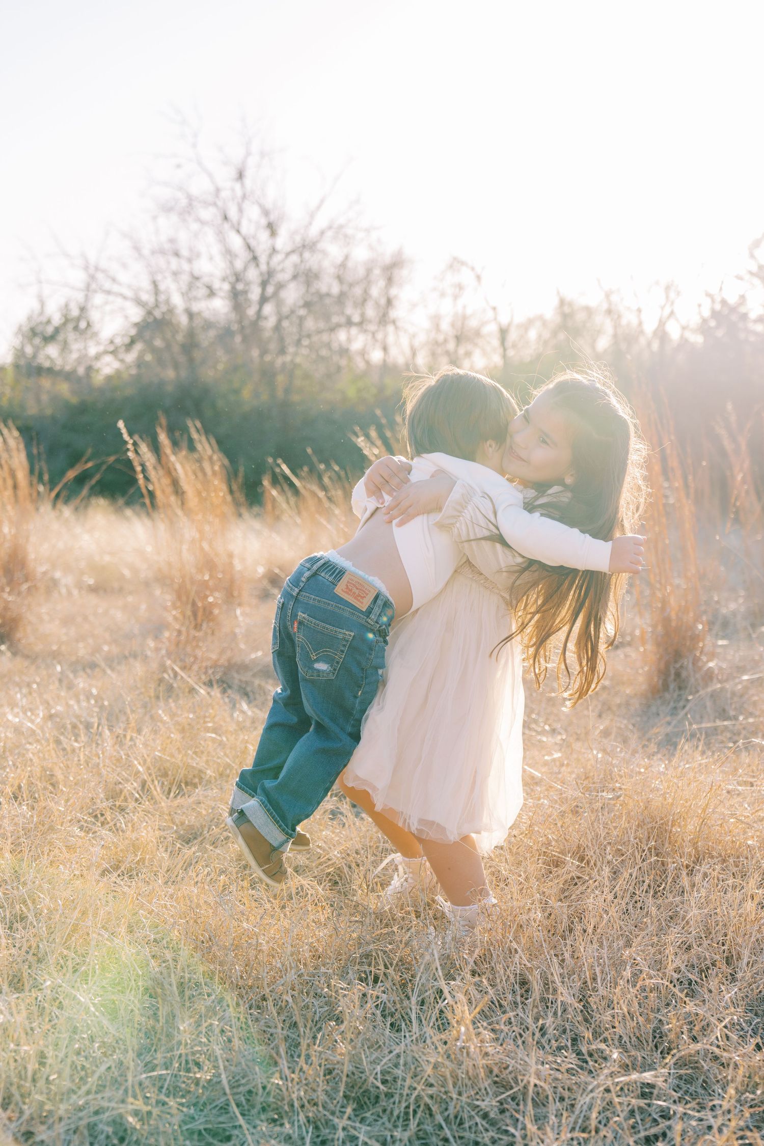 Playful silhouettes twirling through tall grass in warm evening sunlight.