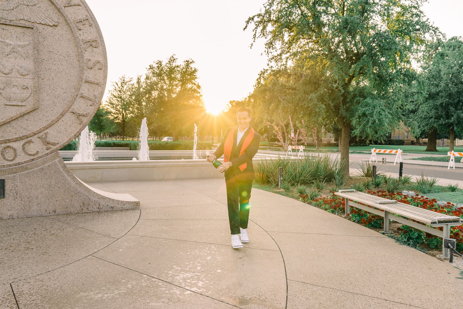Stone archway frames a serene garden path at sunset with benches and lush greenery in the background.