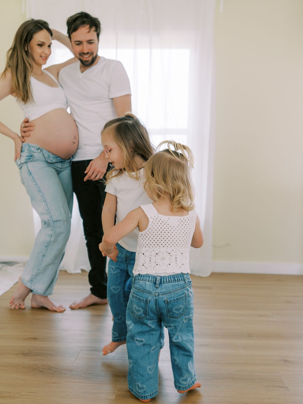 Candid moments of family playtime in a minimalist white room with wood flooring.