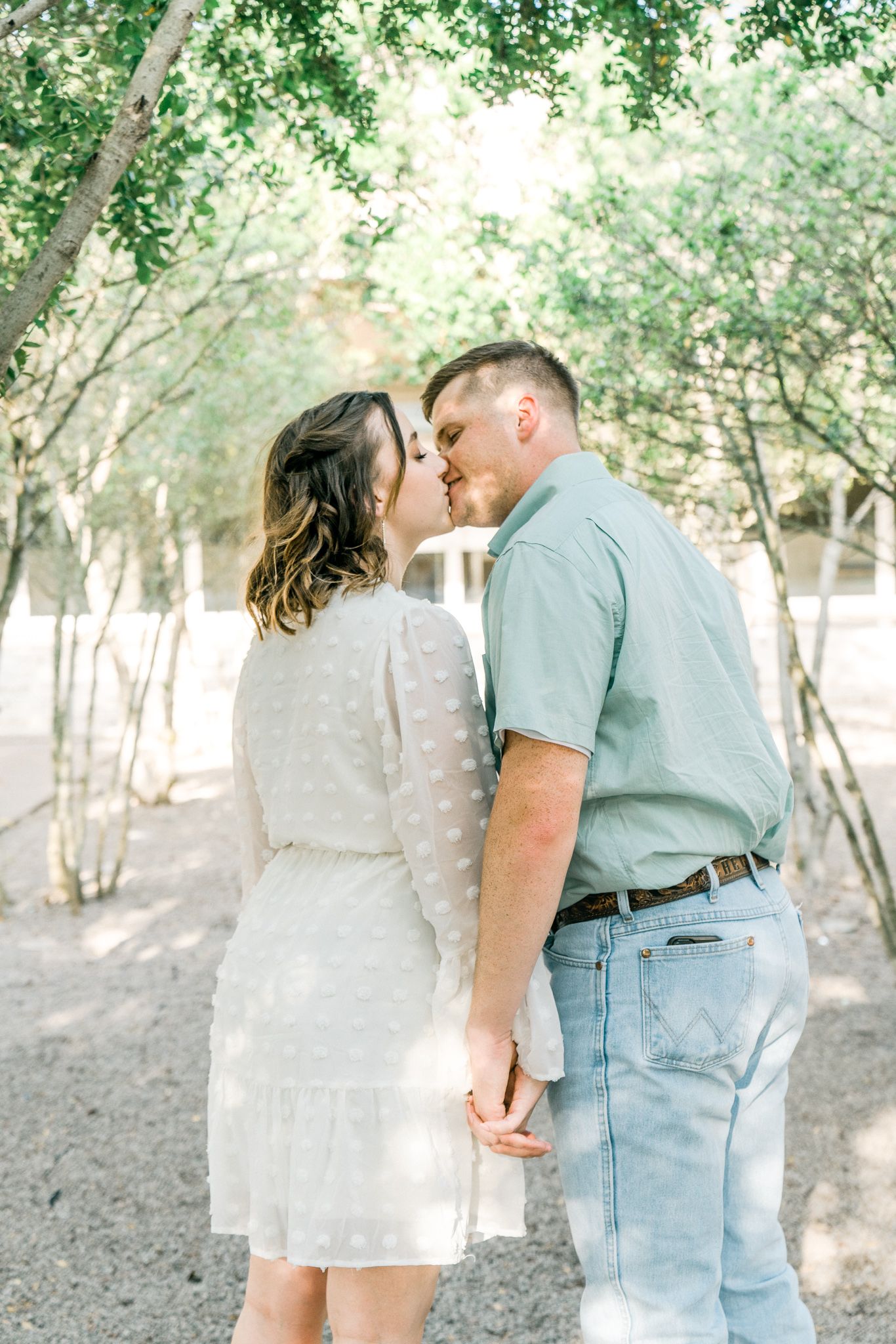 A tender moment shared between a couple among blooming trees in a natural setting.