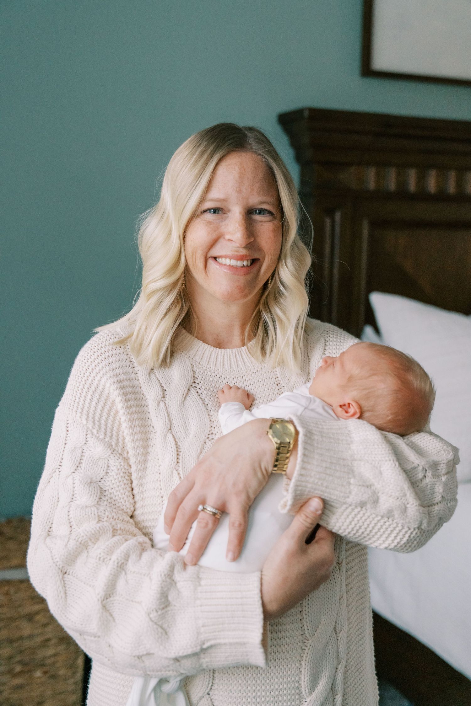 Mother in white sweater sharing joyful moment with newborn baby.