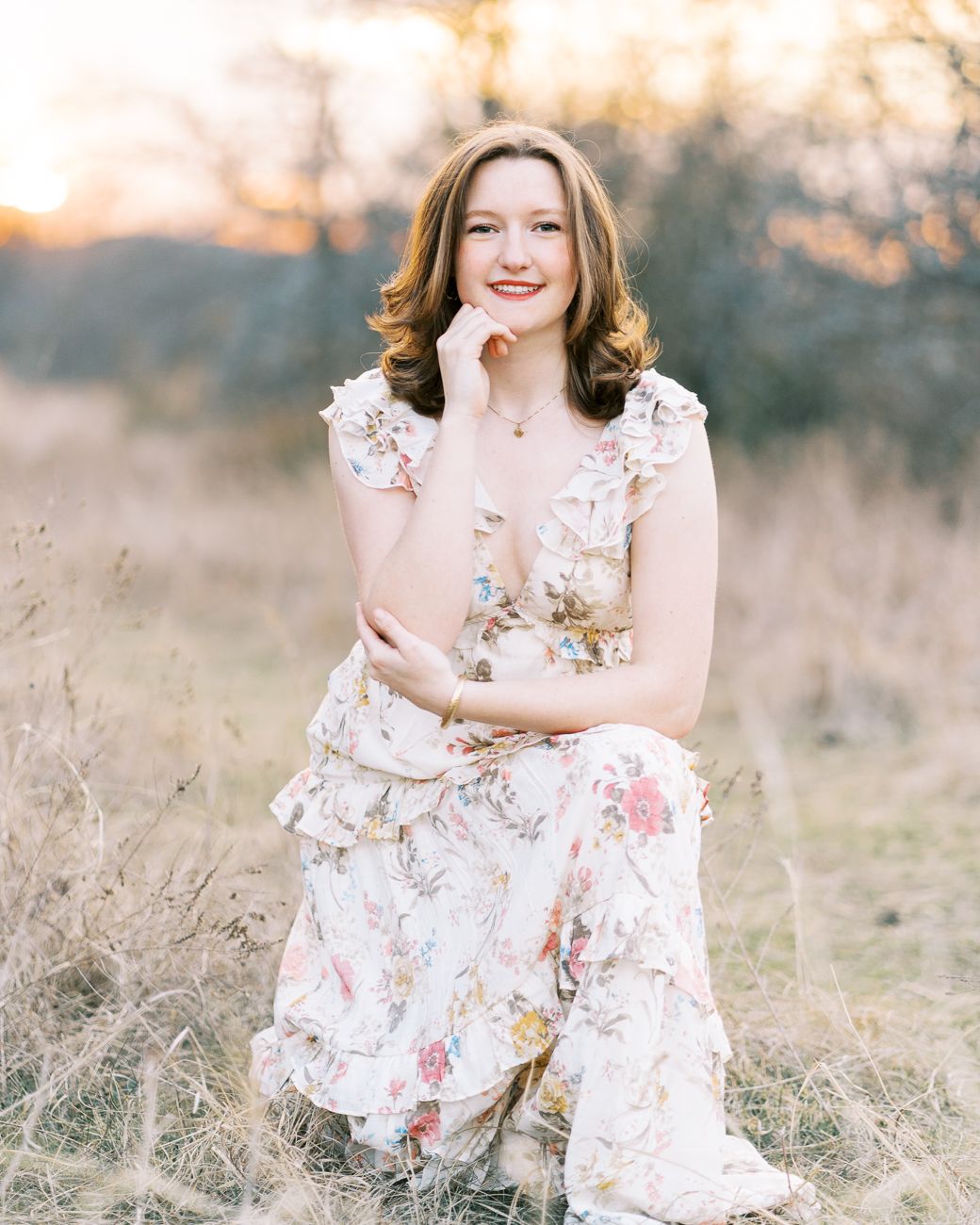 Romantic portrait session featuring a flowy white and pink floral dress in a sun-lit meadow.