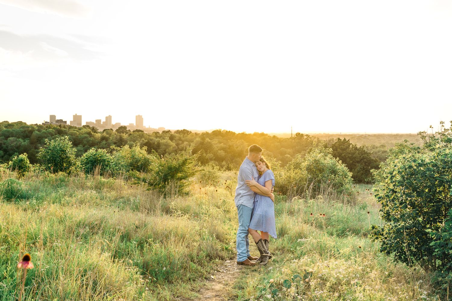 A scenic hilltop meadow glows with golden sunlight during a summer evening photoshoot.
