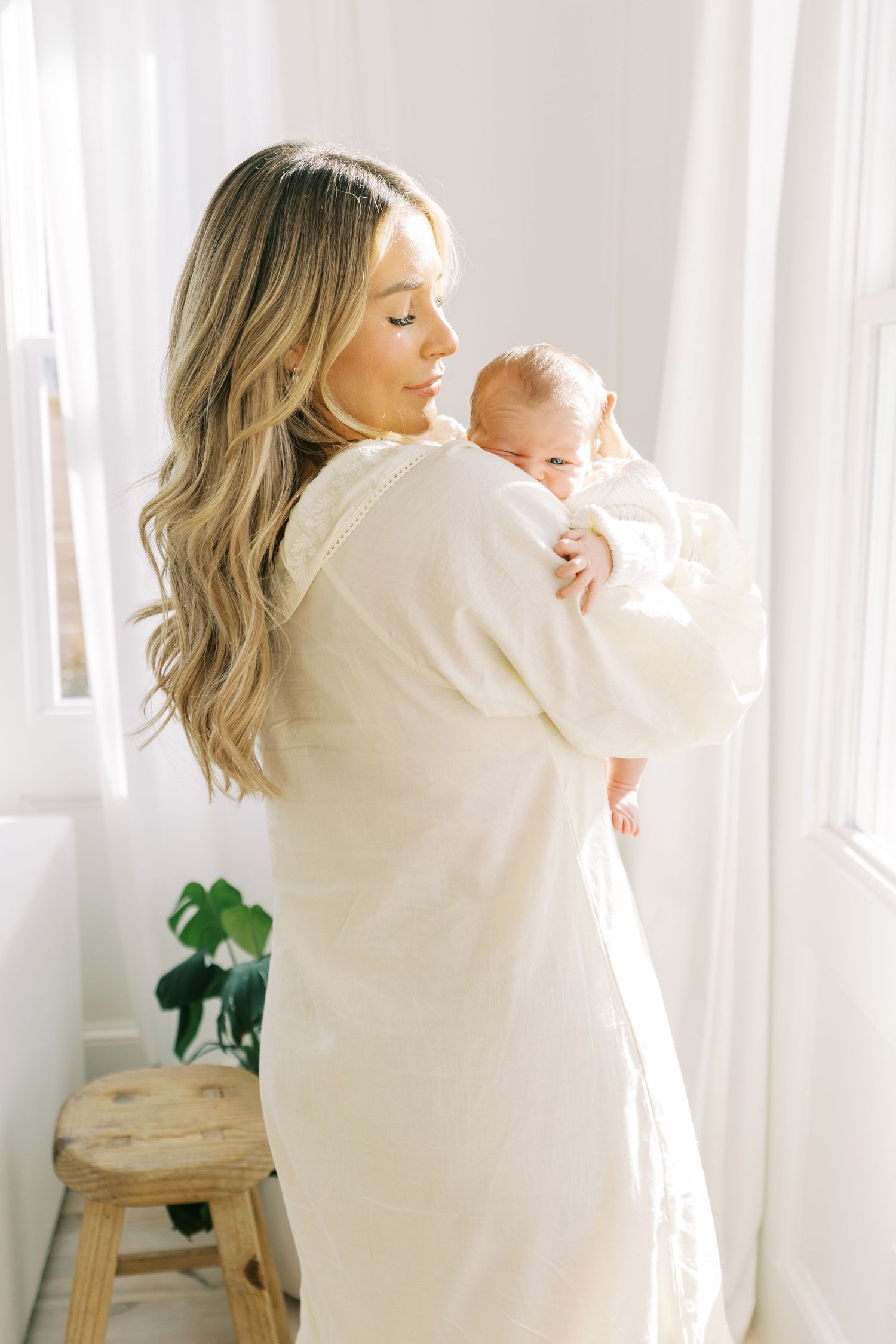 A bright and airy photo session featuring a family in white clothing by a sunlit window.