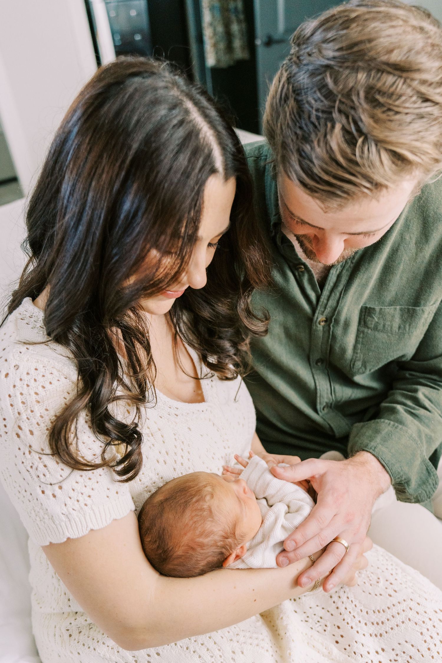 A series of intimate family photos showing parents holding and bonding with their newborn baby in soft natural light.