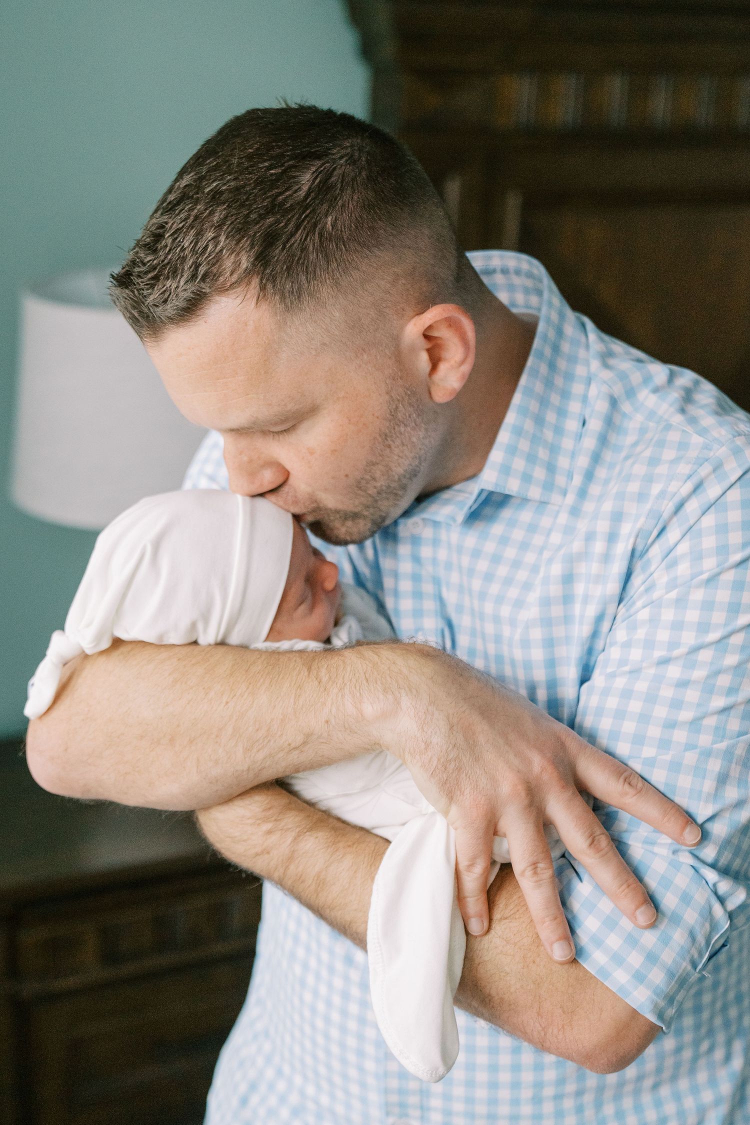 Parent in blue checkered shirt holding sleeping newborn in progressive shots.