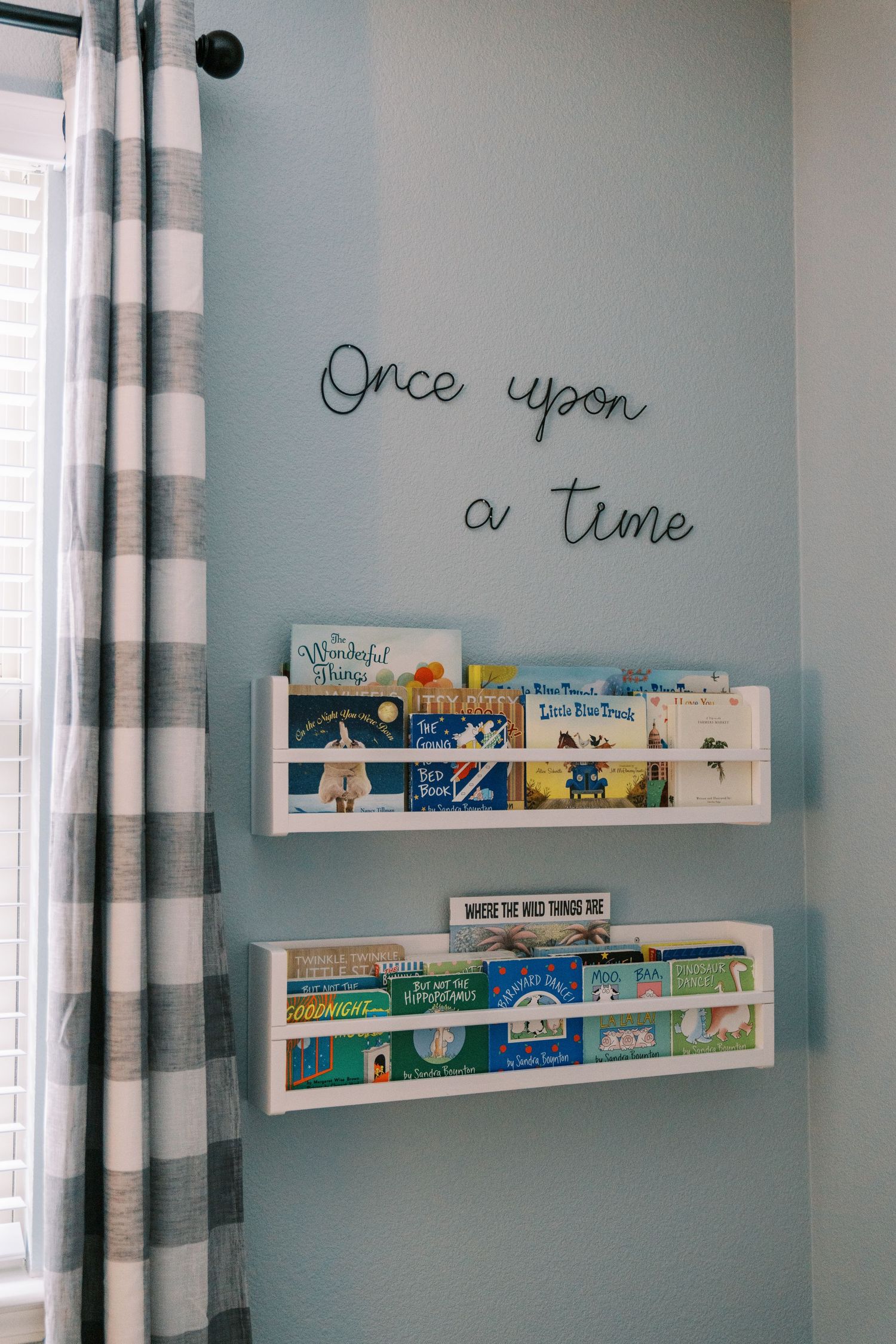 Nursery wall with floating bookshelves and 'Once upon a time' text decor.