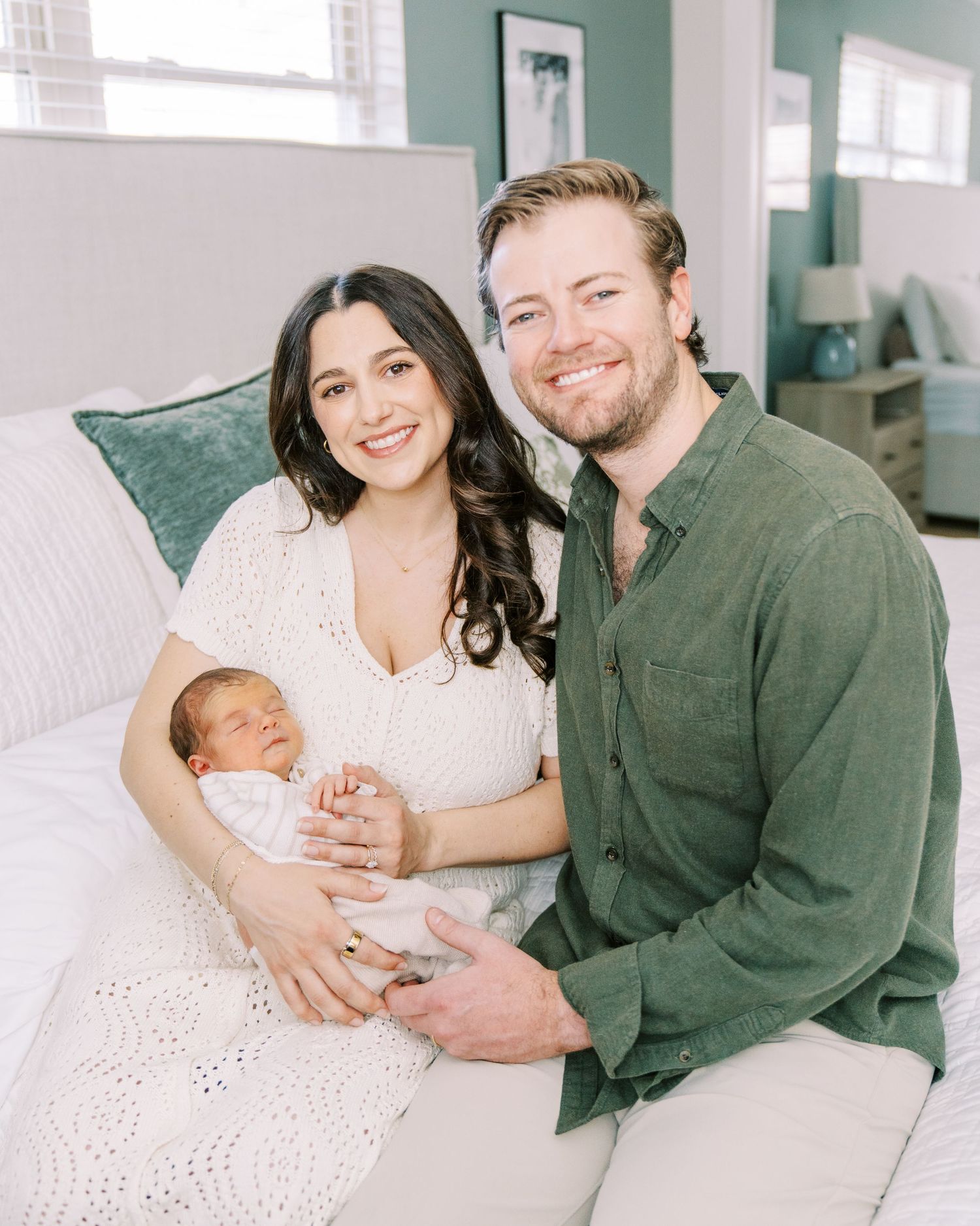 Family photo session in a bright white room with sage green walls showing tender moments with a newborn baby.