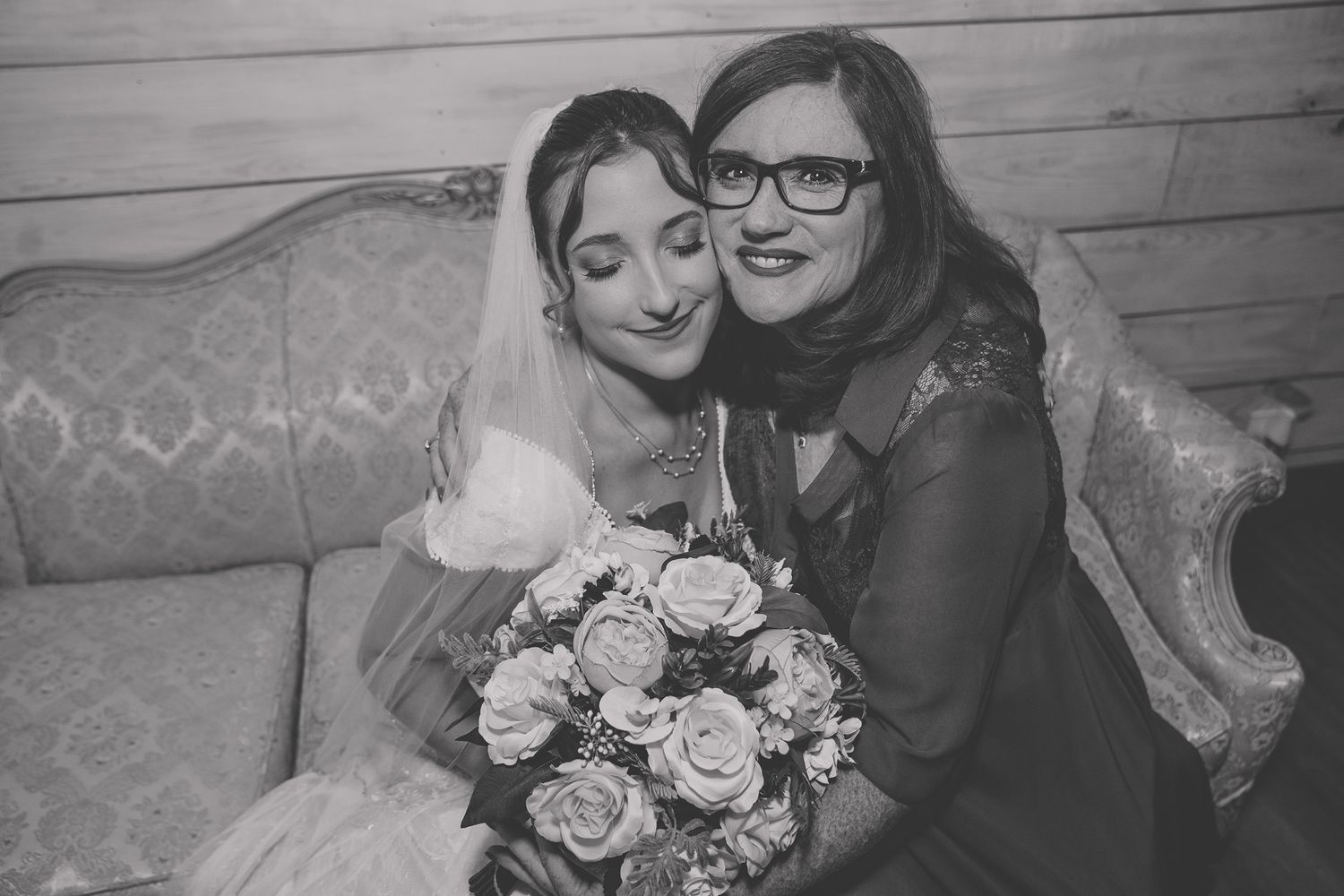 A black and white collage of wedding photos showing couples embracing and holding bouquets against a rustic wooden wall.