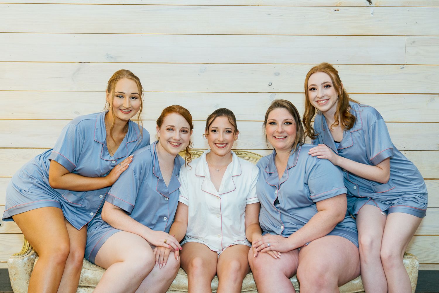 A group wearing matching blue scrubs sits together on wooden steps outdoors.