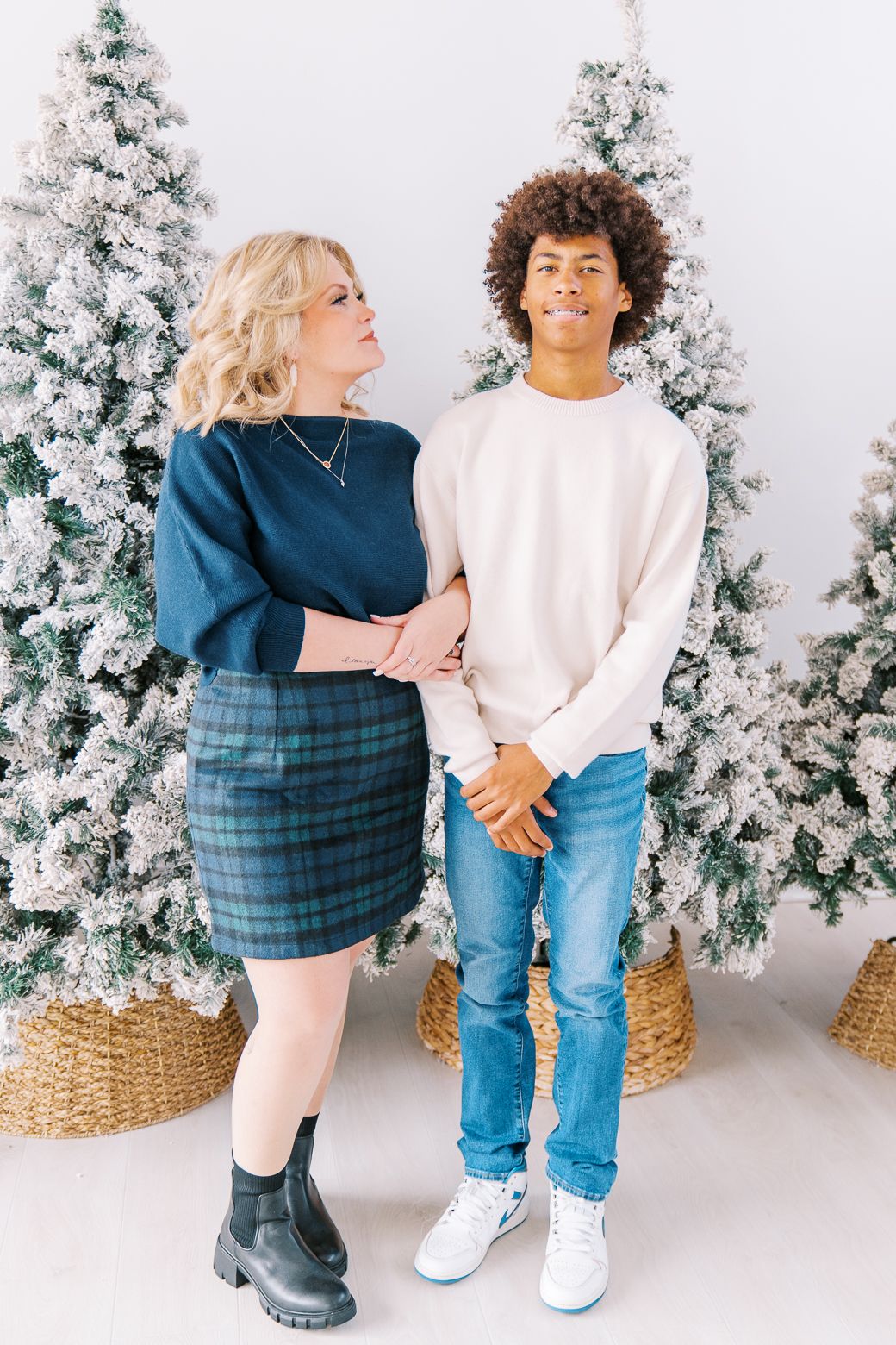 Winter portrait session with snowy Christmas trees and woven baskets as decorative elements.