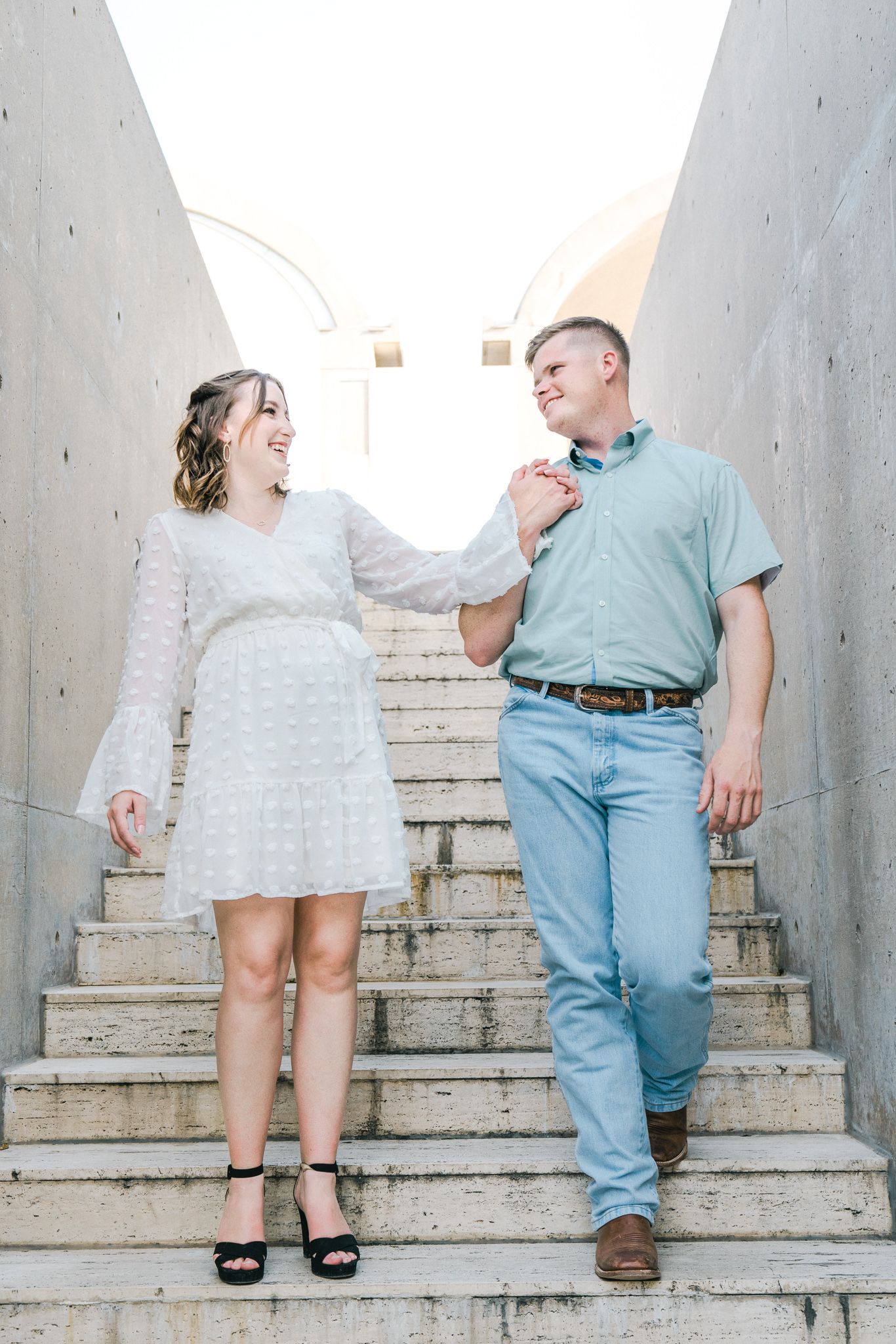 Romantic sequence showing couple ascending concrete steps together in casual summer outfits.
