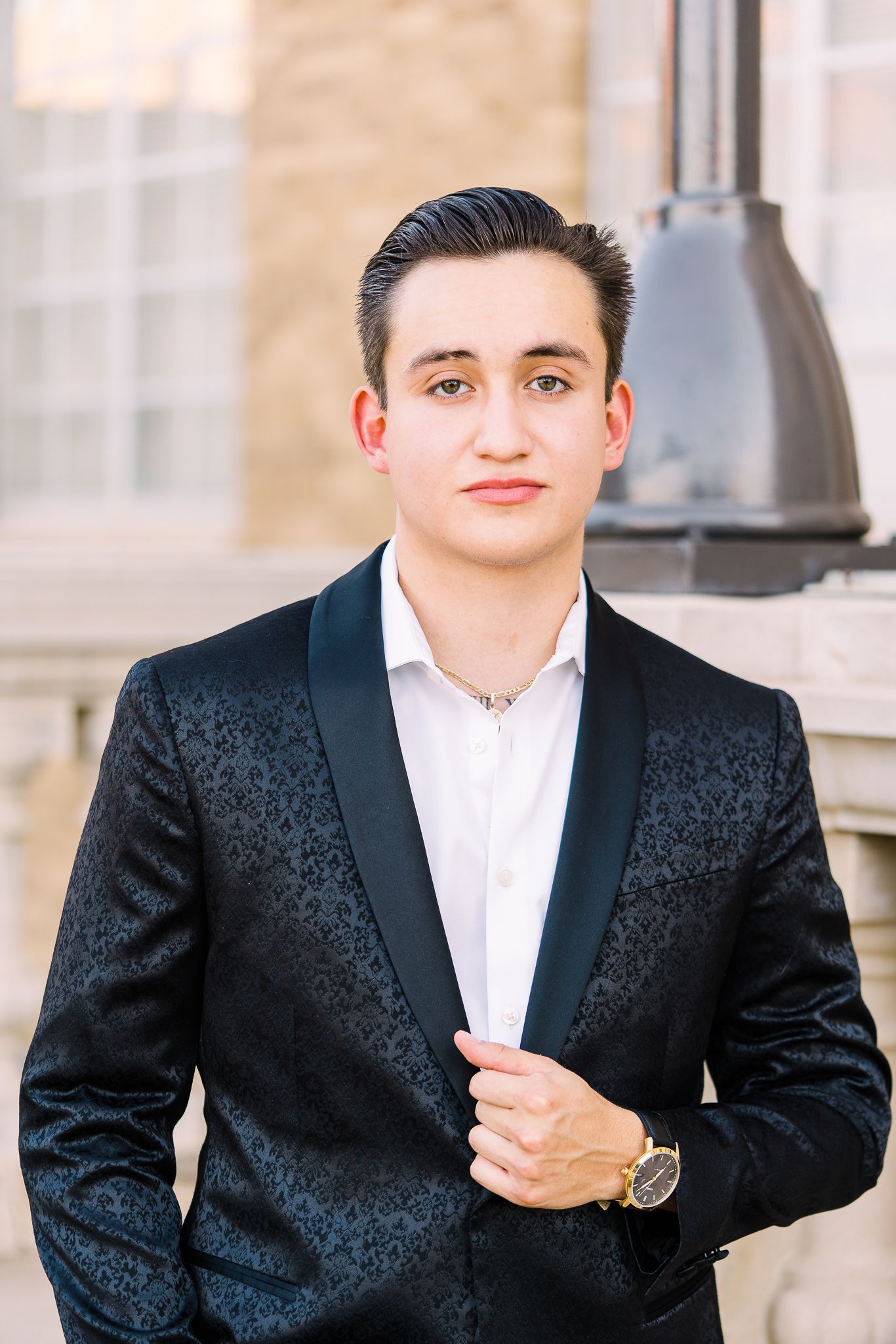 Multiple angles of a person in a black patterned dinner jacket and white shirt posing against a stone building.