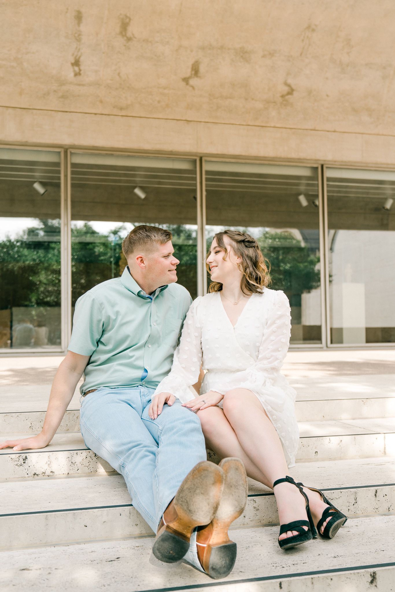 Couple sitting together on concrete steps sharing intimate moments in casual attire.